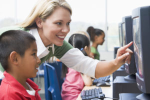 Teacher with little kid at computer